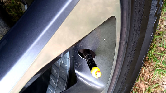 Yellow duck valve cap on a wheel, parked on grass