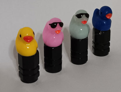 Four duck valve caps in yellow, pink, sage and blue installed on black valve stem caps